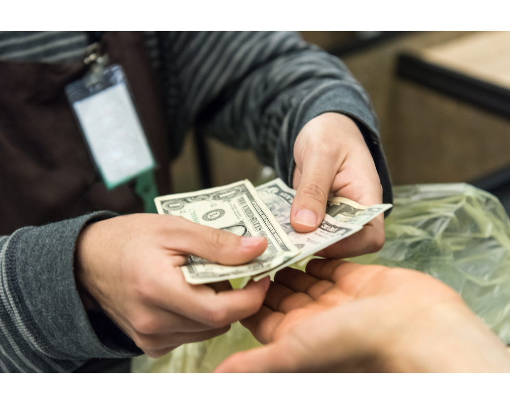 Empleado entregando billetes de dólares estadounidenses a la mano de otra persona