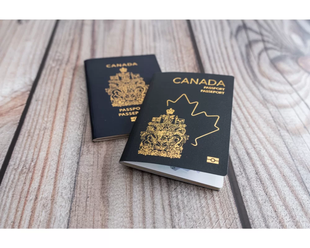 Two Canadian passports resting on a wooden surface